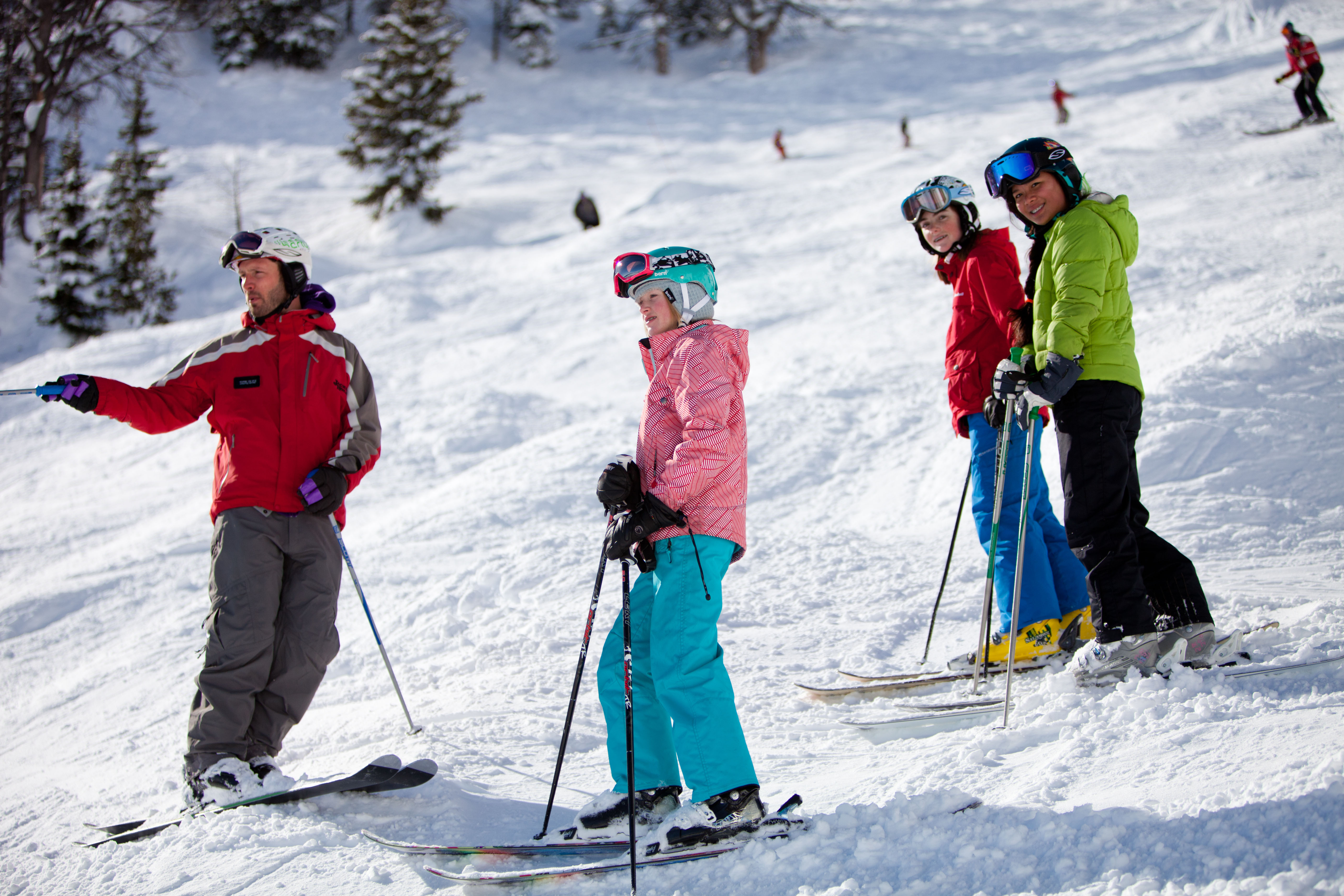 A group of children on skis stand with an instructor on a snowy slope in Jackson Hole, WY.