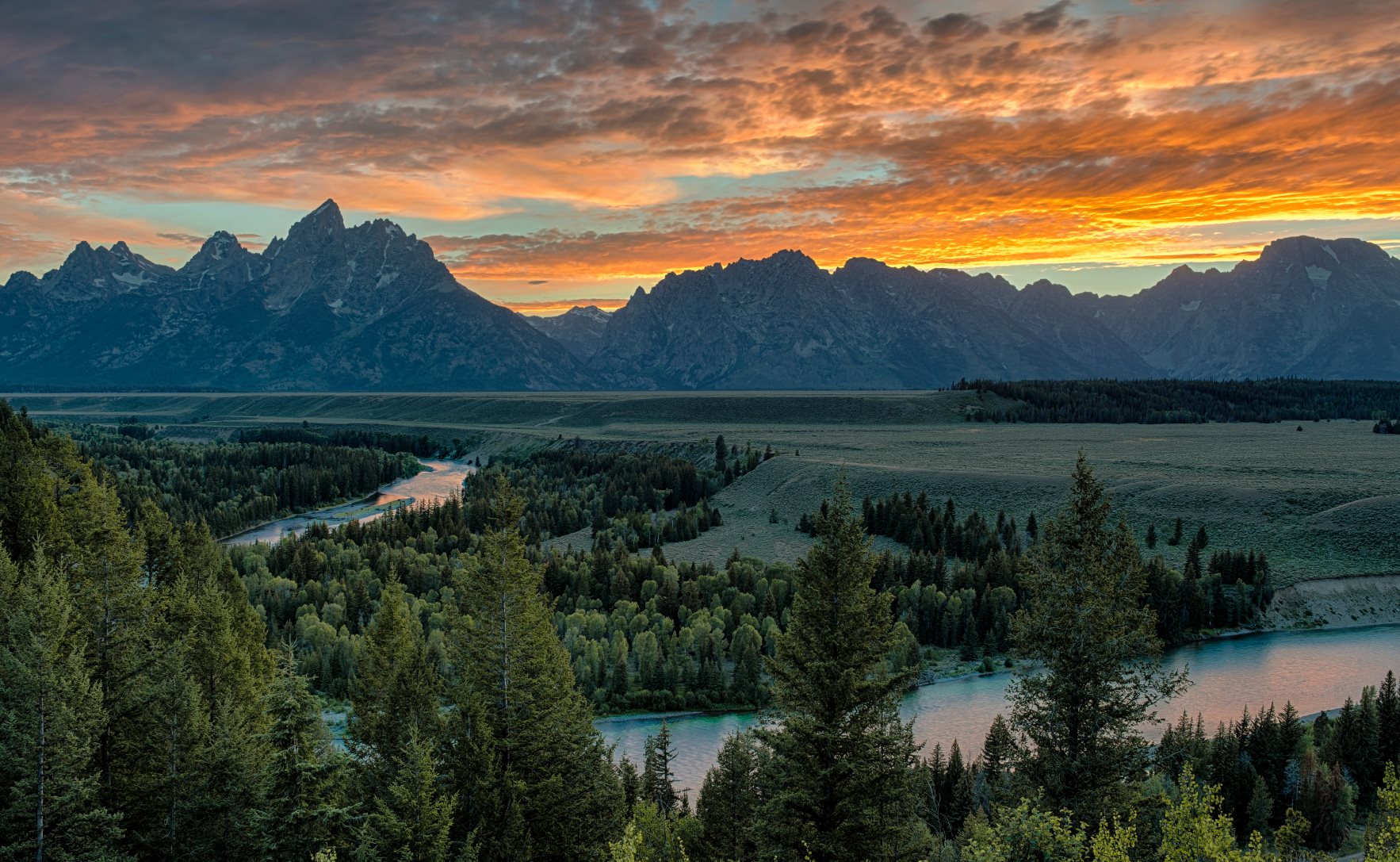 A summer sunset over the snake river and Grand Tetons.