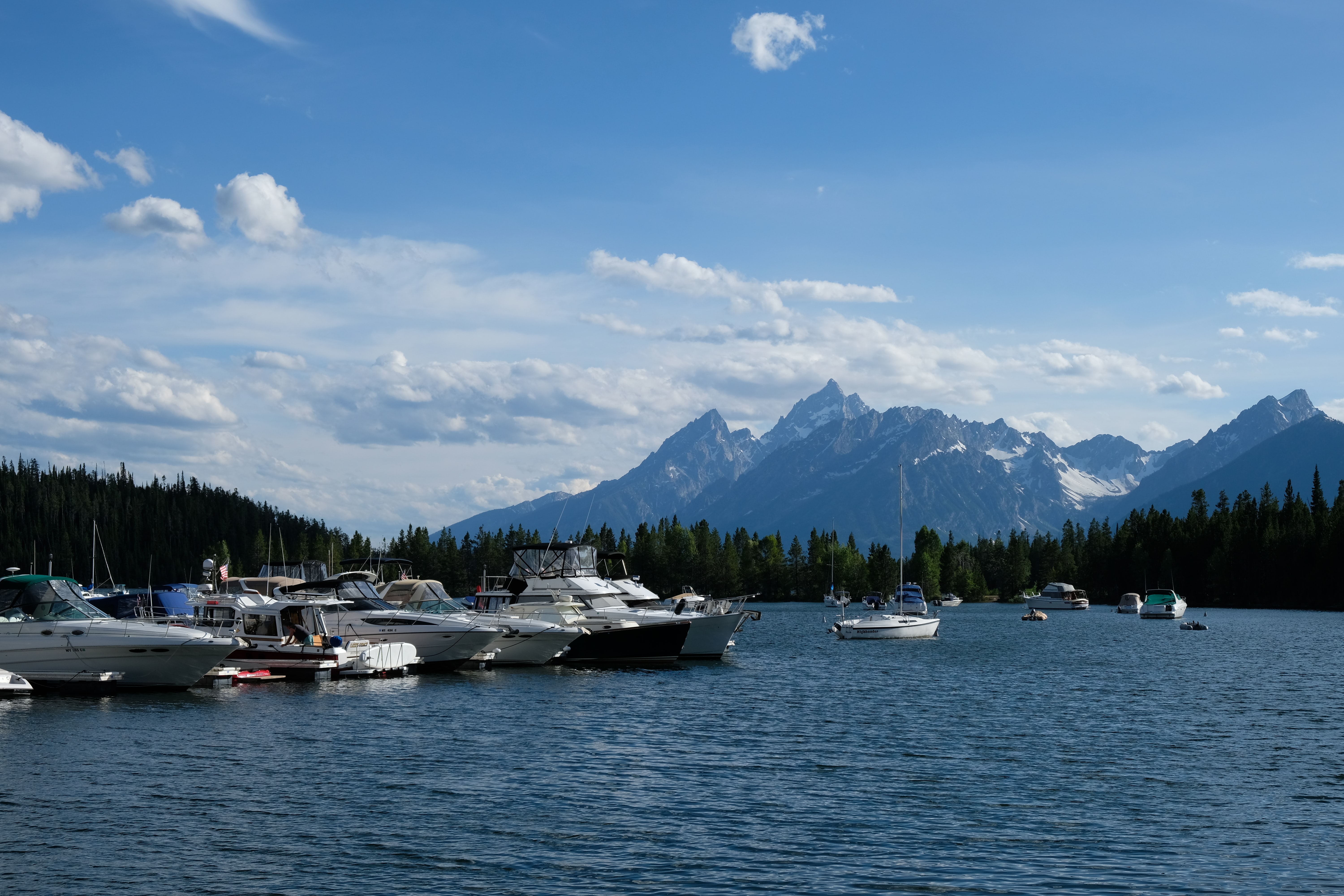 Boats docked and anchored in a lake in front of mountains in Grand Teton National Park.